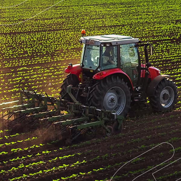 Simule o consórcio de pesados Embracon e descubra como alavancar o seu negócio sem juros e sem entrada Trator puxando uma semeadora através de um campo sob a luz do sol