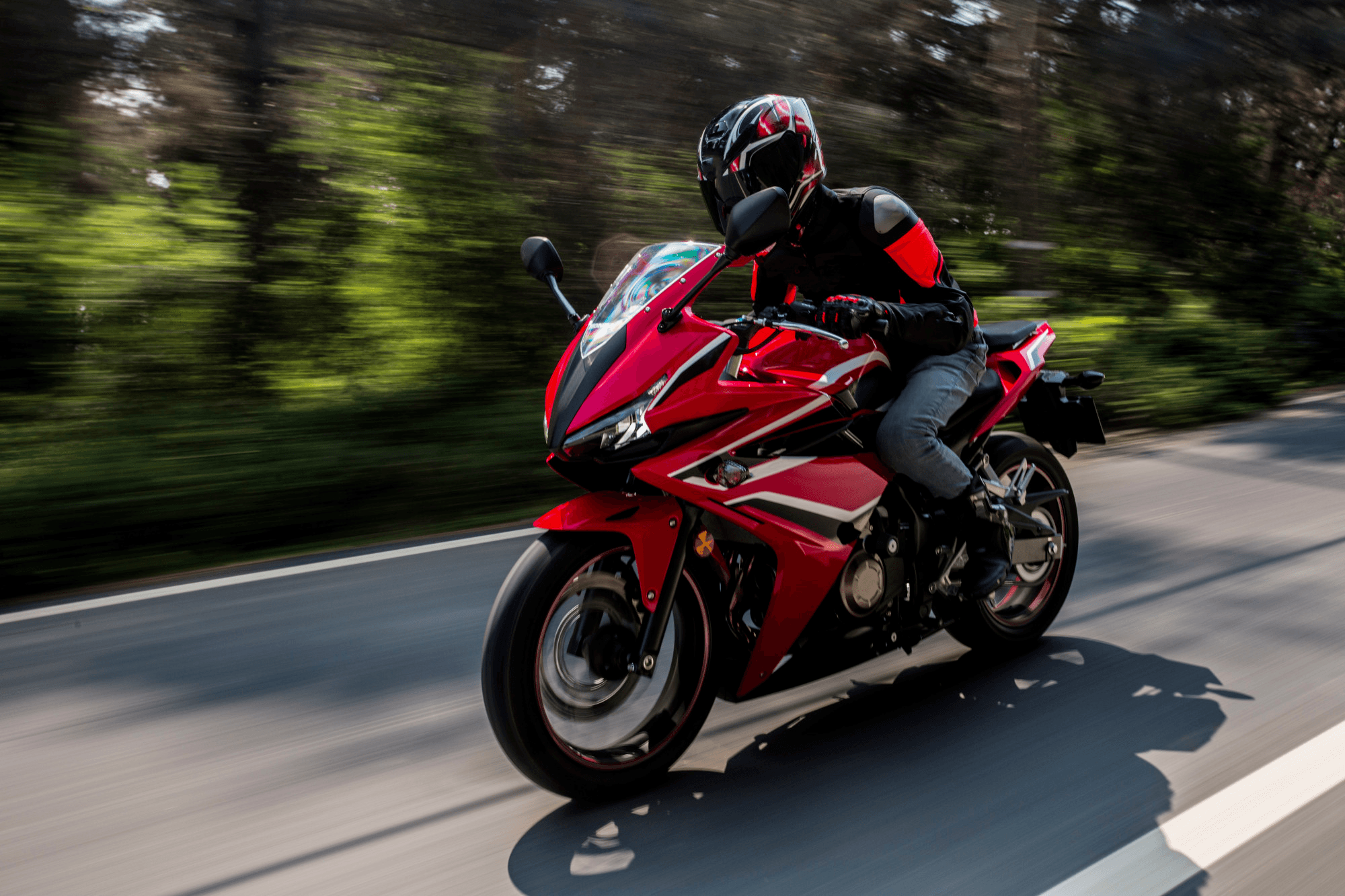 No consórcio de motos Embracon você conquista a sua liberdade com simplicidade e segurança, sem juros e sem entrada! Pessoa com sua moto adquirida pelo consórcio Embracon pilotando por estrada com árvores ao redor